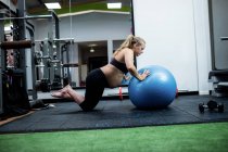 Беременная женщина упражняется с фитнес-мяч в тренажерном зале — стоковое фото