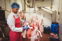Carnicero pegando pegatinas de códigos de barras en la carne roja en el almacén de la carnicería - foto de stock