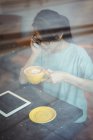 Jovem mulher falando no celular enquanto toma café no café — Fotografia de Stock
