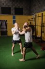 Longitud completa de dos boxeadores tailandeses practicando boxeo en el gimnasio - foto de stock