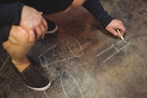 Cropped image of Glassblower drawing diagram on floor at glassblowing factory — Stock Photo