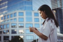 Young woman text messaging on mobile phone at street — Stock Photo