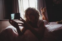 Beautiful woman taking photo on mobile phone in bedroom at home — Stock Photo