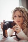 Woman looking at digital camera in bedroom at home — Stock Photo