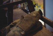 Primer plano de guantes de soplado de vidrio en la mesa en la fábrica de soplado de vidrio - foto de stock