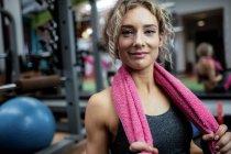 Porträt einer schönen Frau mit einem Handtuch um den Hals im Fitnessstudio — Stockfoto