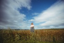Женщина стоит на пшеничном поле в солнечный день в сельской местности — стоковое фото
