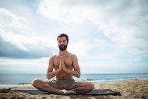 Homme effectuant du yoga sur la plage — Photo de stock