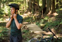 Atlético adolescente usando capacete de bicicleta na floresta — Fotografia de Stock