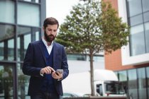 Businessman using mobile phone outside office — Stock Photo