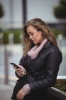 Красивая женщина в кожаной куртке и со смартфоном на улице — стоковое фото