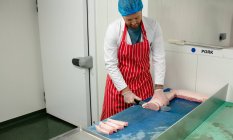 Carniceiro cortando carne no açougue — Fotografia de Stock