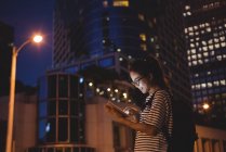 Giovane donna che utilizza tablet digitale sulla strada di notte — Foto stock