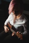 Женщина играет на гитаре в музыкальной школе — стоковое фото