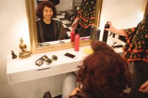 Mujer sonriente sentada frente al espejo en la peluquería - foto de stock