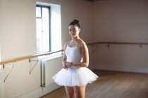 Ballerina steht in weißem Tutu im Studio und blickt in die Kamera — Stockfoto