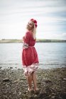 Rear view of Happy blonde woman wearing flower tiara and standing near river — Stock Photo