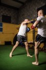 Two athletic thai boxers practicing boxing in gym — Stock Photo