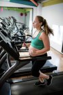Mulher grávida se exercitando em esteira na academia — Fotografia de Stock