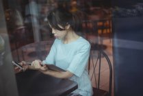 Junge Frau mit Handy und digitalem Tablet im Café — Stockfoto