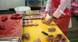 Mid section of butcher preparing chicken and steak roll in butchers shop — Stock Photo
