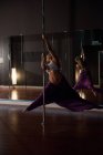 Dançarina de pólo praticando pole dance no estúdio escuro — Fotografia de Stock