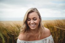 Lächelnde Frau steht an sonnigem Tag im Weizenfeld — Stockfoto