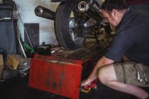 Mechanic using hydraulic lift in workshop — Stock Photo