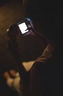 Nahaufnahme einer Frau, die ihr Handy benutzt, während sie nachts Eis isst — Stockfoto