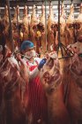 Carnicero pegando pegatinas de códigos de barras en la carne roja en el almacén de la carnicería - foto de stock