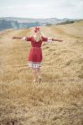 Visão traseira da mulher loira despreocupada em pé no campo com os braços abertos — Fotografia de Stock