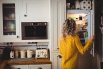 Frau sucht zu Hause im Kühlschrank in Küche nach Essen — Stockfoto