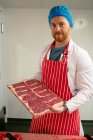 Metzger hält Tablett mit Steaks in Metzgerei — Stockfoto
