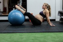 Беременная женщина упражняется с мячом в тренажерном зале — стоковое фото
