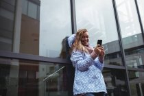 Красивая улыбающаяся женщина в обманщице и со смартфоном — стоковое фото