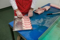 Sección media del carnicero que organiza filetes en bandeja en la carnicería - foto de stock