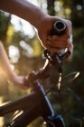 Mãos de atleta masculino de pé com bicicleta de montanha no parque à luz do sol — Fotografia de Stock