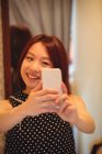 Joven mujer asiática tomando selfie desde el teléfono móvil en la tienda boutique - foto de stock
