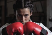 Portrait de femme confiante en gants de boxe à la salle de fitness — Photo de stock