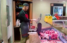 Açougueiro verificando o peso da carne no balcão em loja de carne — Fotografia de Stock