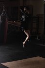 Boxeador practicando boxeo con saco de boxeo en gimnasio - foto de stock