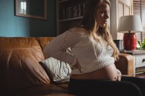 Mulher grávida atraente relaxante na sala de estar em casa — Fotografia de Stock
