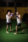 Vista laterale di due pugili thai che praticano la boxe in palestra — Foto stock