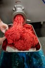М'ясо фаршу виходить з м'ясорубки в м'ясному магазині — стокове фото