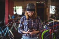 Woman adjusting vintage camera in bicycle shop — Stock Photo
