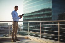 Бізнесмен, використовуючи цифровий планшет, стоячи на балконі в офісі — стокове фото