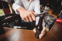 Gros plan du barman ouvrant une bouteille de bière au comptoir du bar — Photo de stock