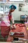 М'ясник рубає червоне м'ясо в м'ясному магазині — стокове фото