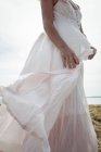Partie médiane de la femme insouciante en robe blanche debout dans le champ — Photo de stock