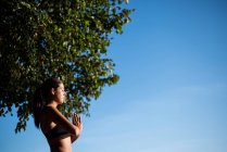 Vista lateral da bela mulher realizando ioga no jardim no dia ensolarado — Fotografia de Stock